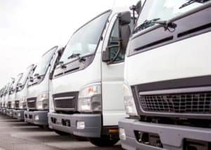 A row of white commercial delivery trucks used for logistics and transportation services, showcasing a professional fleet for business operations.