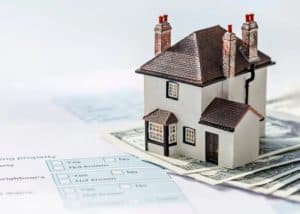 Miniature house model placed on currency notes, symbolising property investment and home buying in the UK.